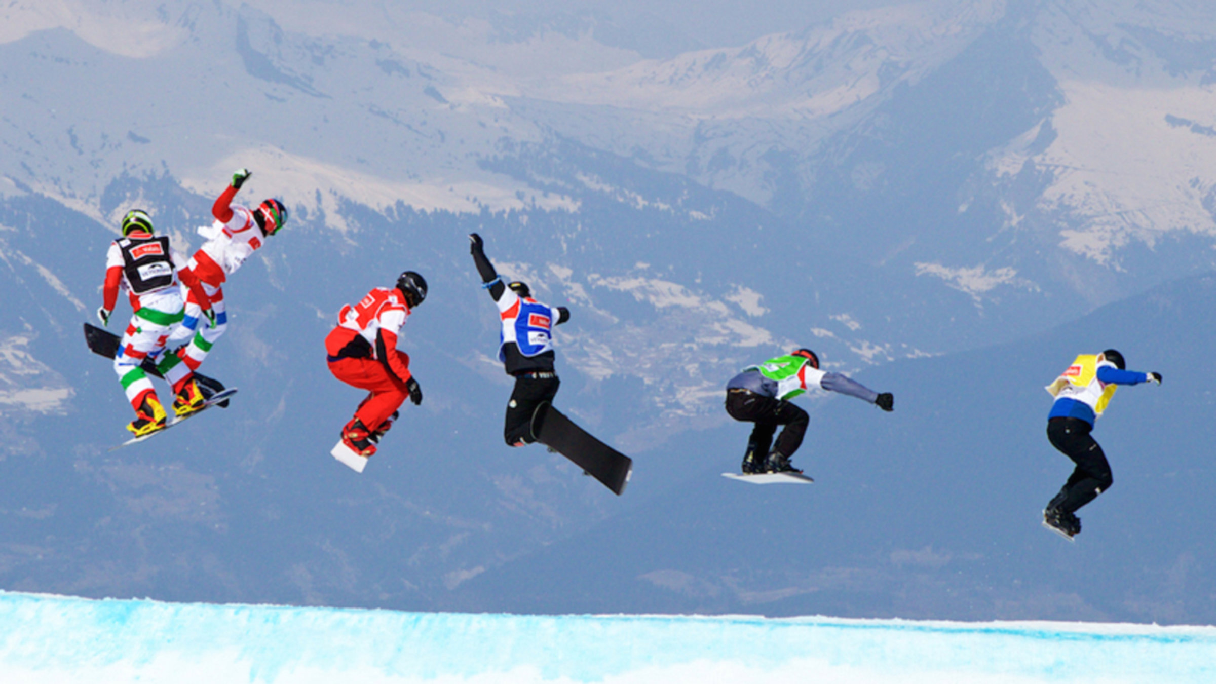 A Group Of People Enjoying Snowborading And Flying Over